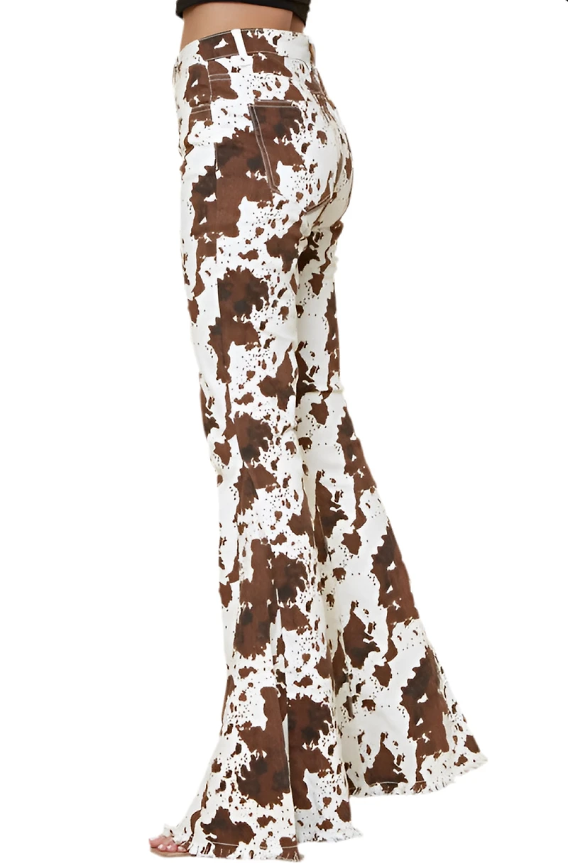 SAINTS  AND HEARTS: COW PRINT FLARED DENIM PANTS