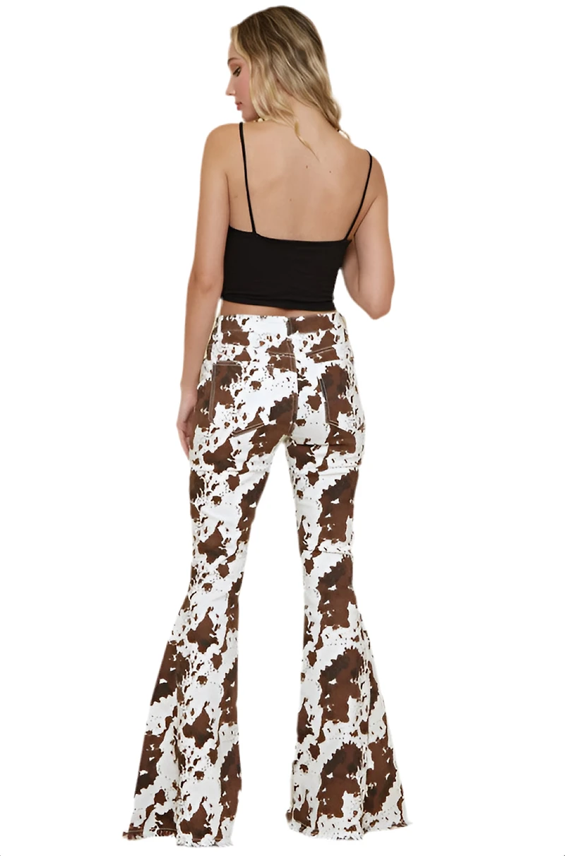 SAINTS  AND HEARTS: COW PRINT FLARED DENIM PANTS