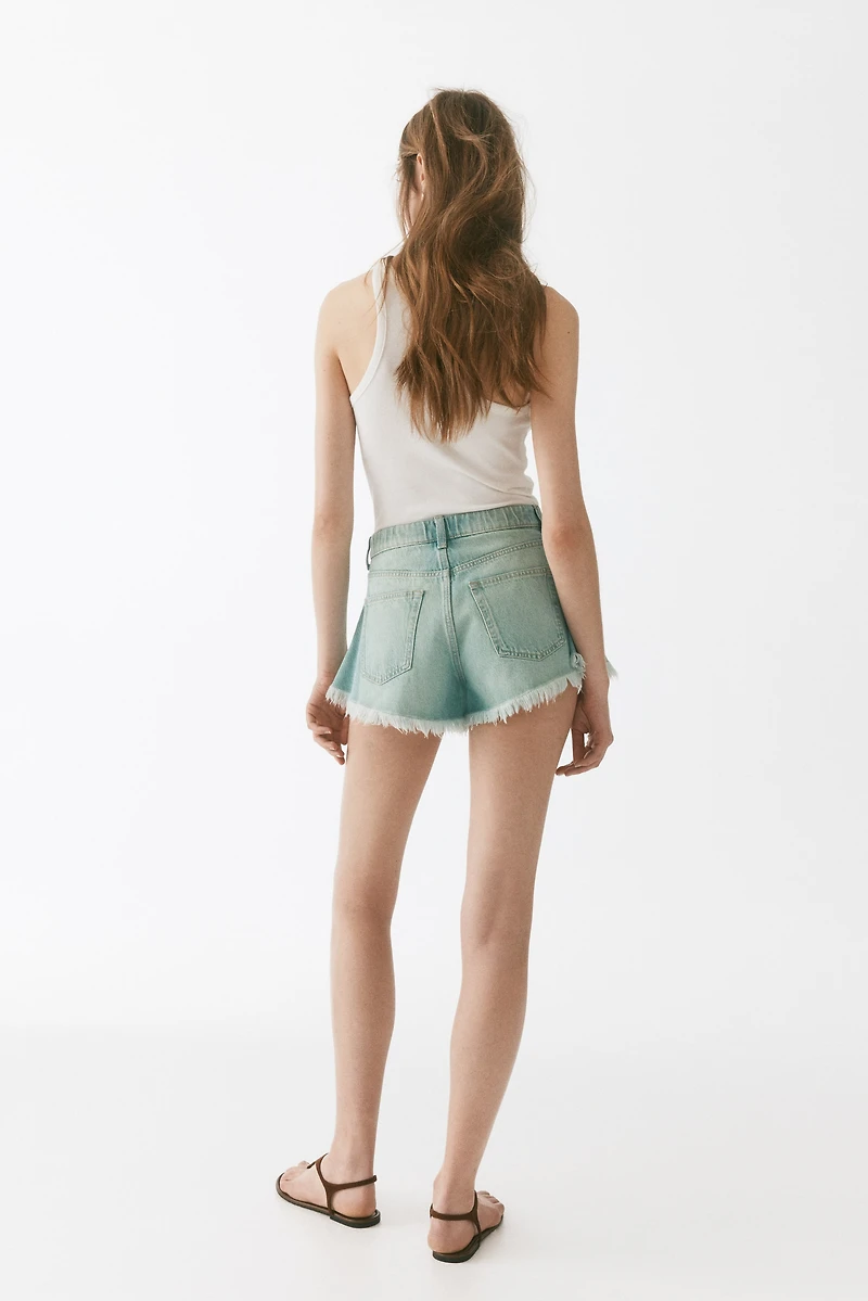Short frangé en denim
