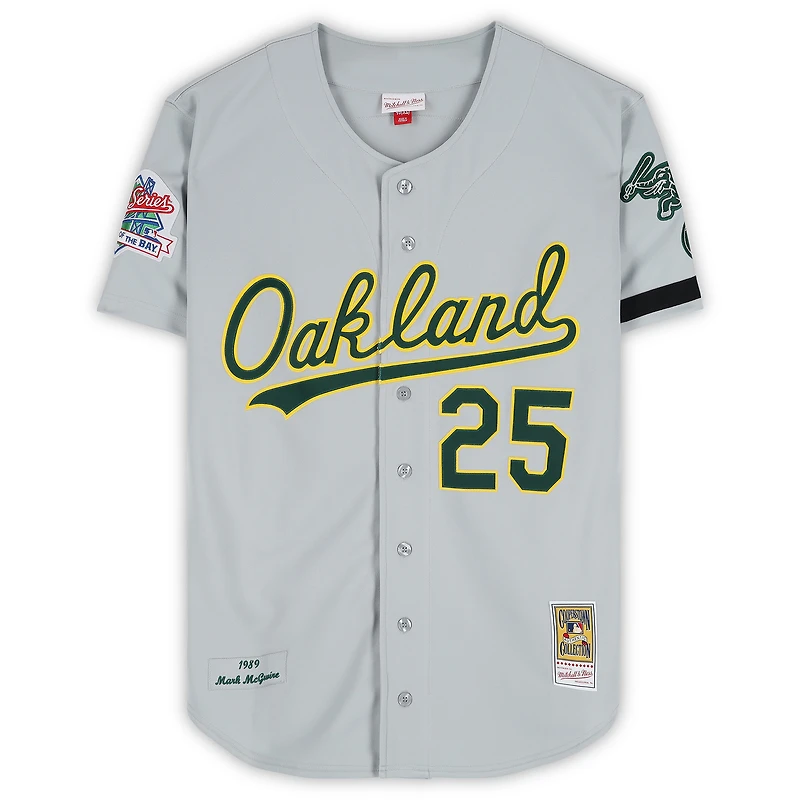 Maillot authentique gris Mitchell & Ness des Athletics d'Oakland, autographié par Mark McGwire, lors des Séries mondiales de 1989, avec inscription « Champions des Séries mondiales 89 ».
