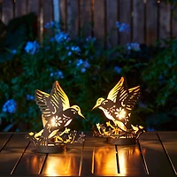 Glitzhome® 9.75" Metal Flying Hummingbird Silhouette Solar Powered Edison Bulb Outdoor Lanterns, 2ct.
