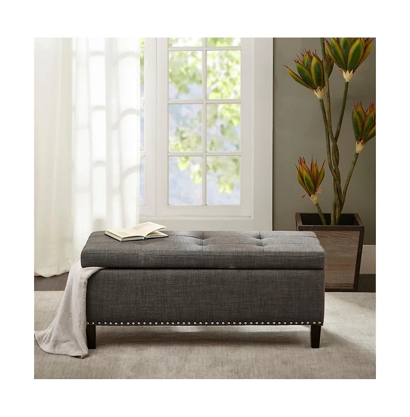 Modern tufted storage bench with soft-close lid, grey linen upholstery, button tufting, black wood legs, and interior for bedroom or entryway.
