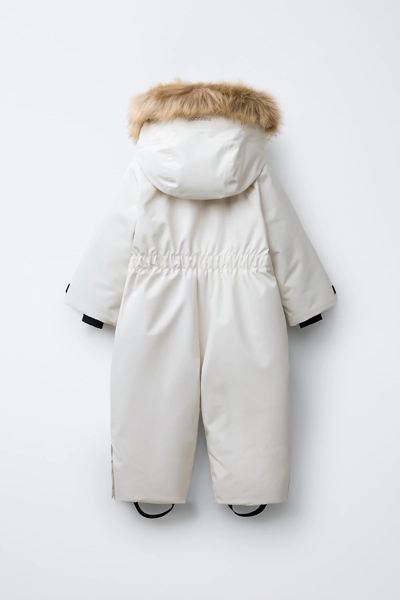 WATER RESISTANT AND WINDPROOF RECCO® SYSTEM SKI COLLECTION LONG JUMPSUIT WITH FAUX FUR HOODIE