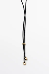 Collier avec pendentif coquillage et pompon