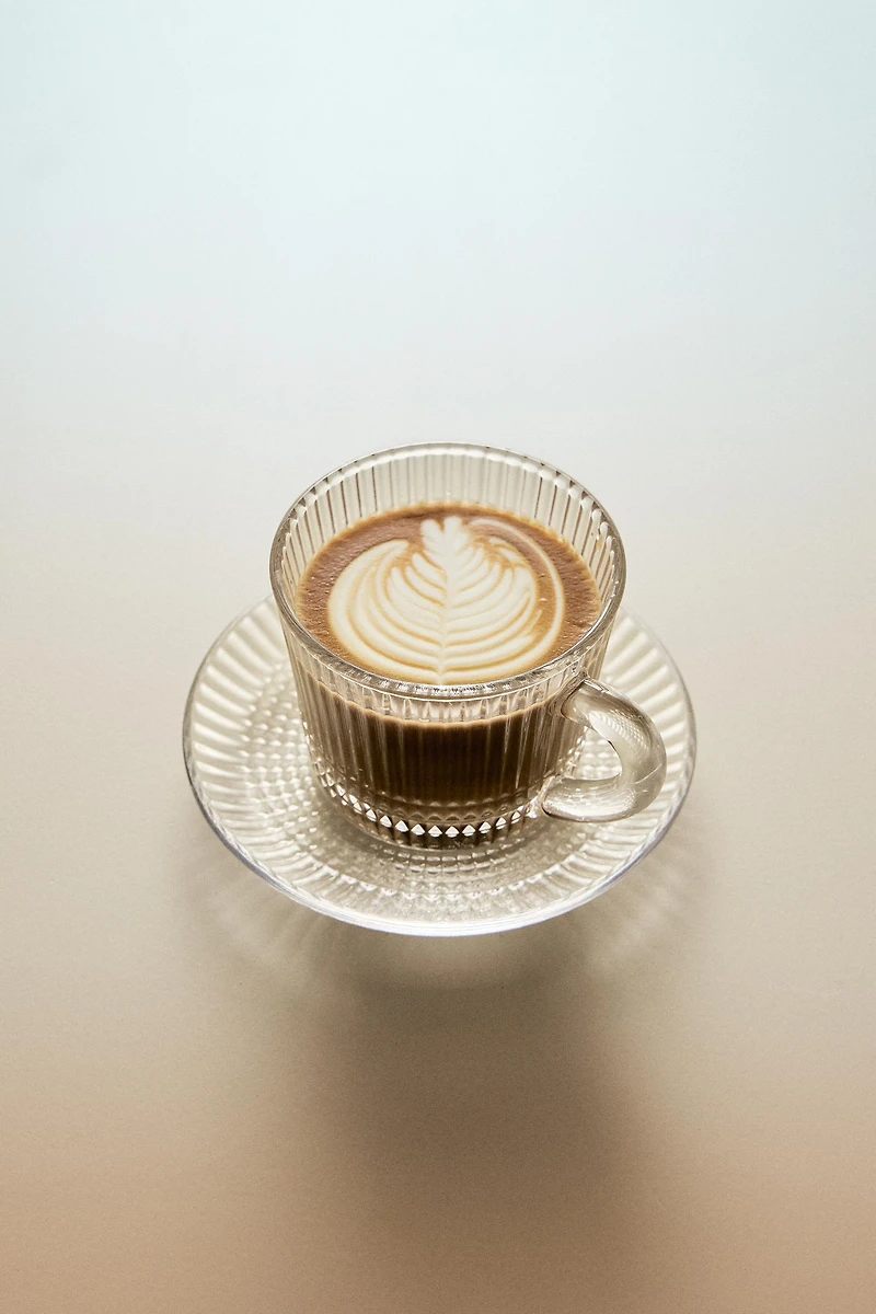 GLASS COFFEE CUP WITH SAUCER AND RAISED GEOMETRIC DESIGN.