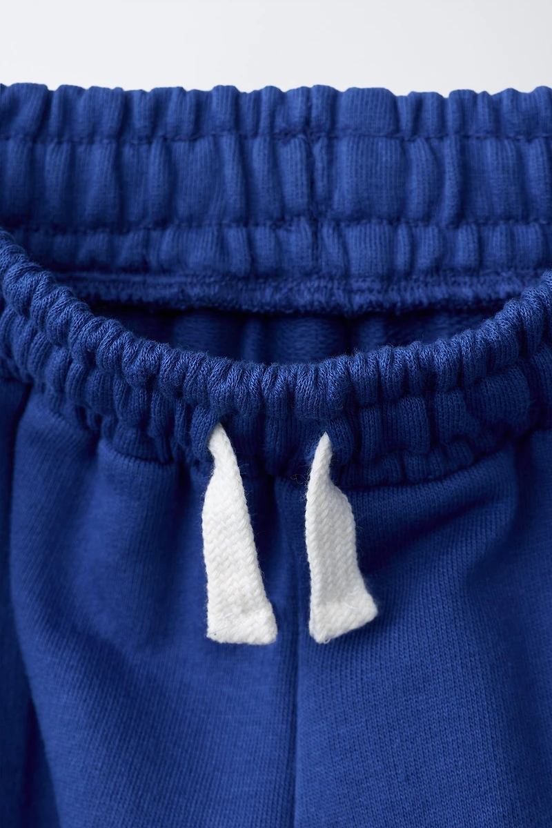 PANTALON À JAMBES LARGES ET BANDES SUR LES CÔTÉS