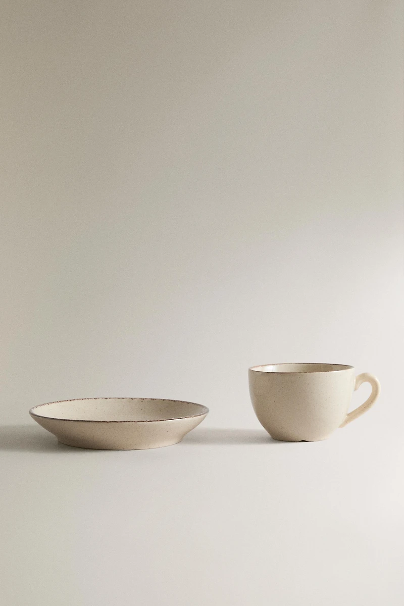 STONEWARE TEACUP AND SAUCER WITH DISTRESSED RIM
