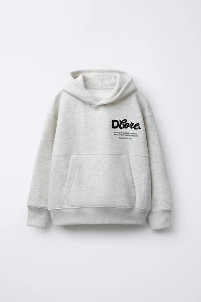 SWEAT À CAPUCHE AVEC INSCRIPTION BOUCLÉE