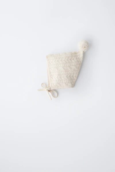 BONNET EN MAILLE À TORSADES ET POMPON