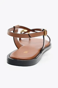 FLAT SANDALS WITH STRAPS AND METAL DETAIL