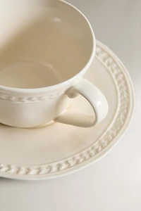 RAISED STONEWARE TEACUP AND SAUCER