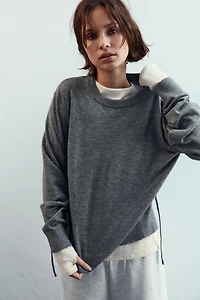 PULL EN MAILLE AVEC OUVERTURE ET CORDONS AU DOS