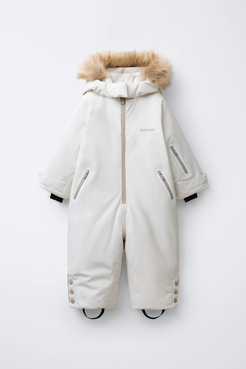 WATER RESISTANT AND WINDPROOF RECCO® SYSTEM SKI COLLECTION LONG JUMPSUIT WITH FAUX FUR HOODIE