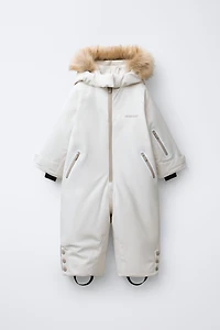 WATER RESISTANT AND WINDPROOF RECCO® SYSTEM SKI COLLECTION LONG JUMPSUIT WITH FAUX FUR HOODIE