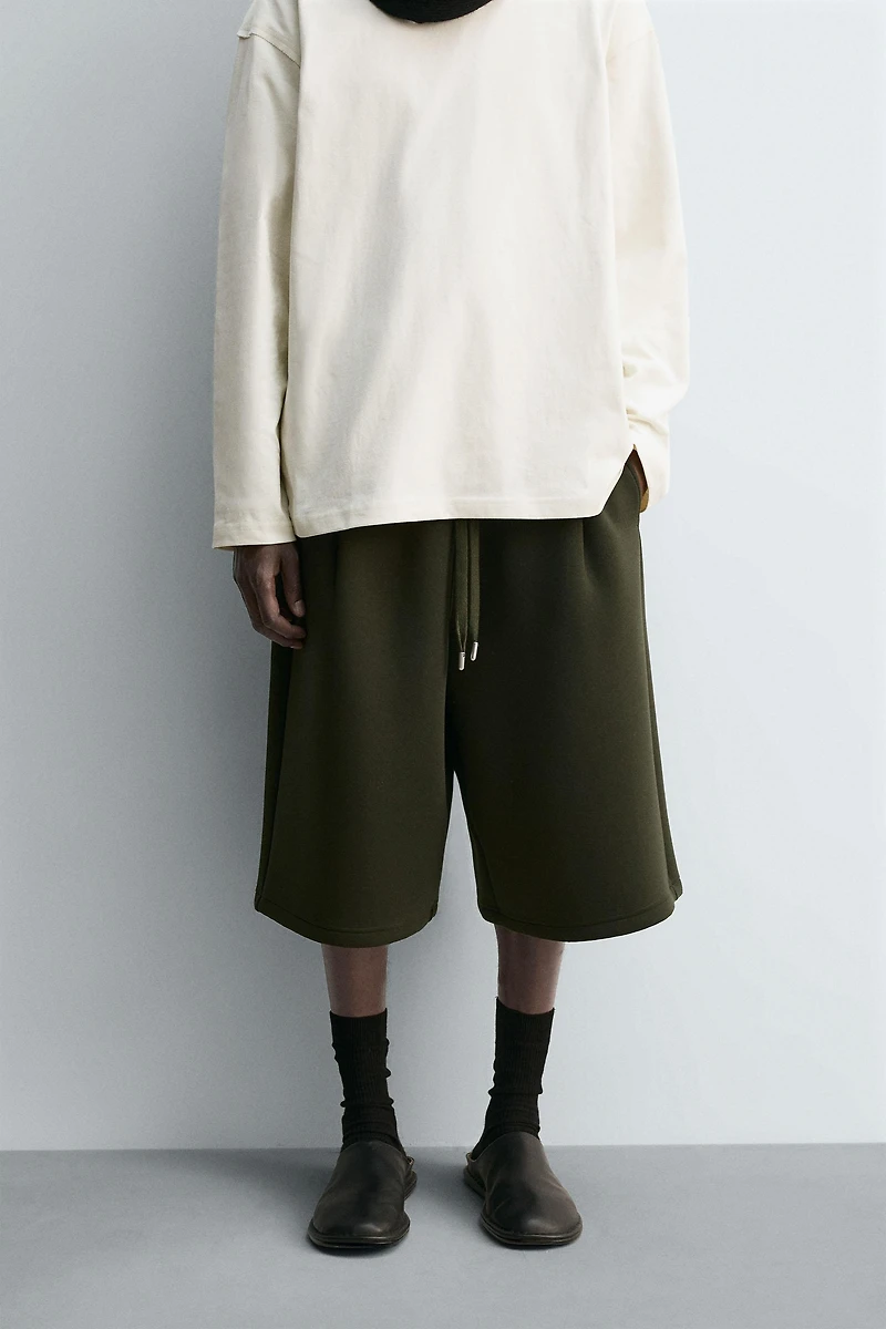 NEOPRENE EFFECT PLEATED LONG BERMUDA SHORTS