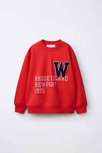 SWEAT IMPRIMÉ INSCRIPTION ET PIÈCE BOUCLÉE