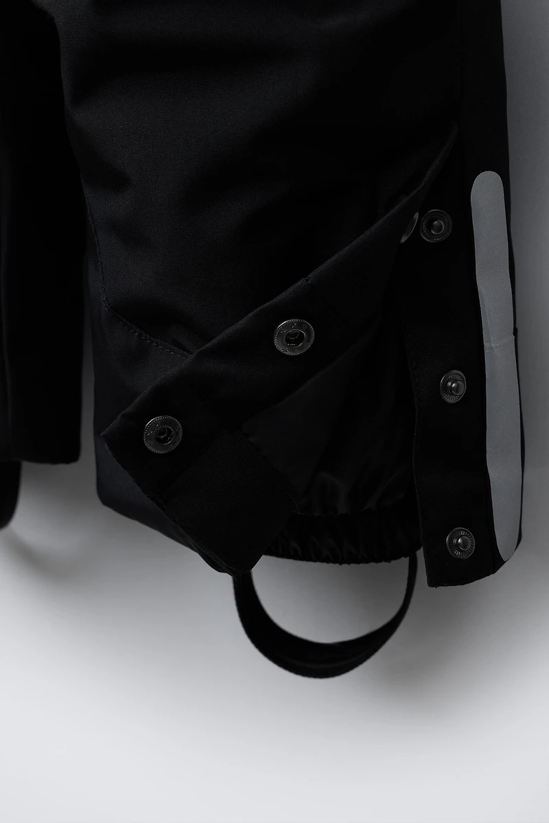 SALOPETTE LONGUE RÉSISTANTE À L'EAU ET AU VENT AVEC POCHES