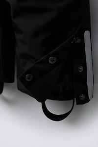 SALOPETTE LONGUE RÉSISTANTE À L'EAU ET AU VENT AVEC POCHES