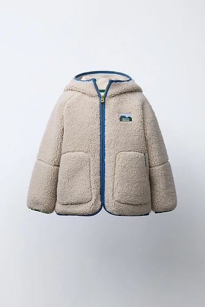 VESTE EFFET MOUTON CAPUCHE LISERÉS CONTRASTE