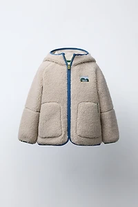 VESTE EFFET MOUTON CAPUCHE LISERÉS CONTRASTE