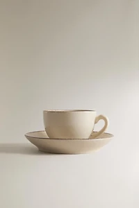 STONEWARE TEACUP AND SAUCER WITH DISTRESSED RIM
