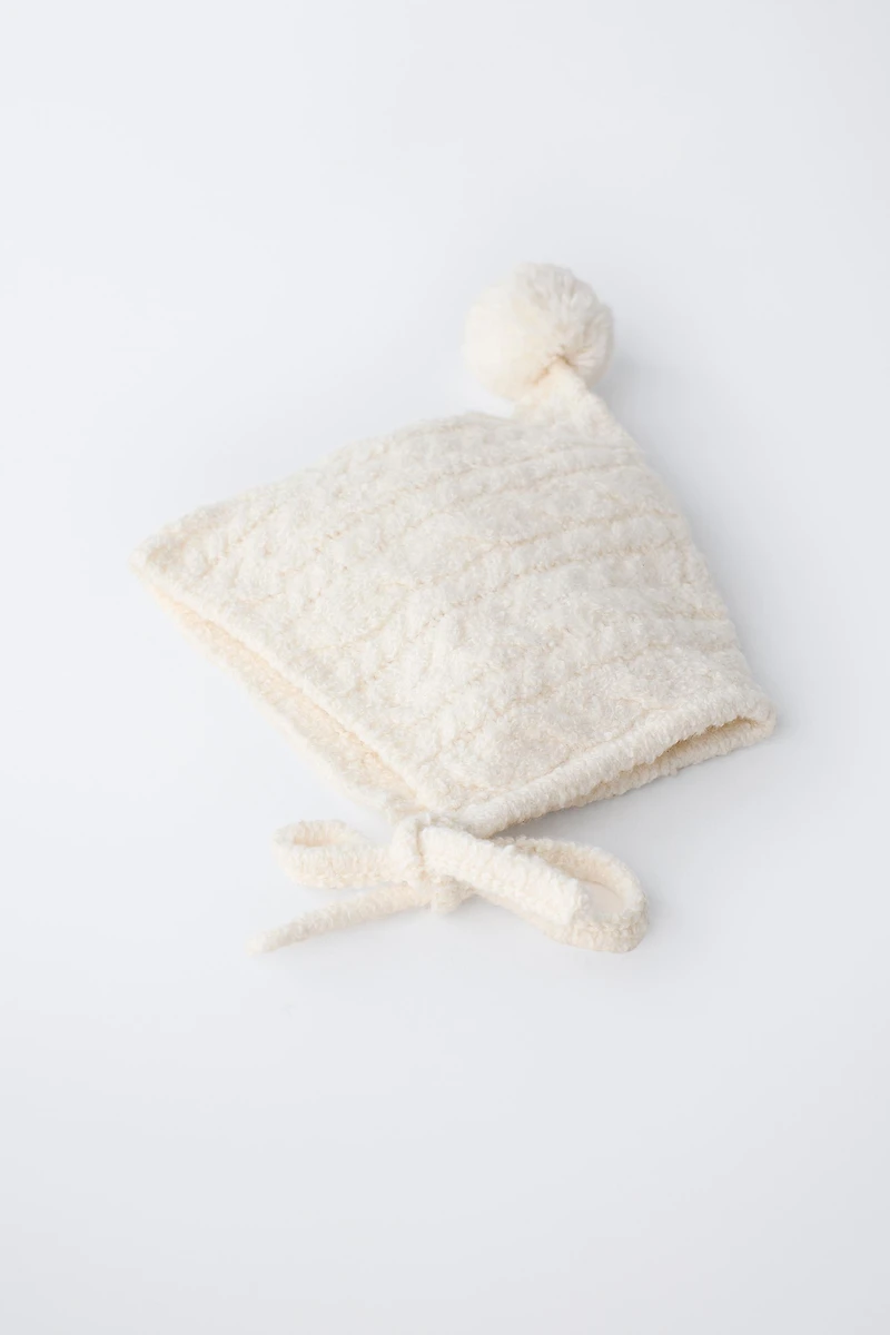 BONNET EN MAILLE À TORSADES ET POMPON