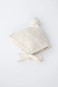 BONNET EN MAILLE À TORSADES ET POMPON