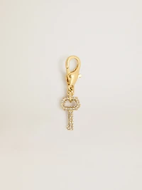 Key-shaped charm in gold-colored brass with crystals