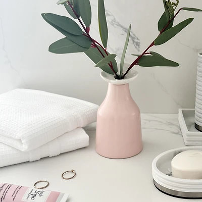 Vase rose avec une fleur blanche
