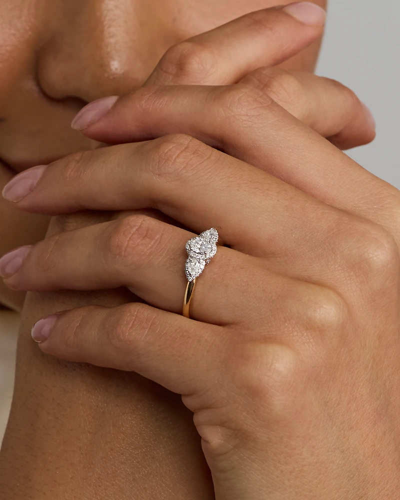 Bague de fiançailles halo en or jaune et blanc 14 carats avec trois diamants ovales forme poire totalisant 0,69 carat.