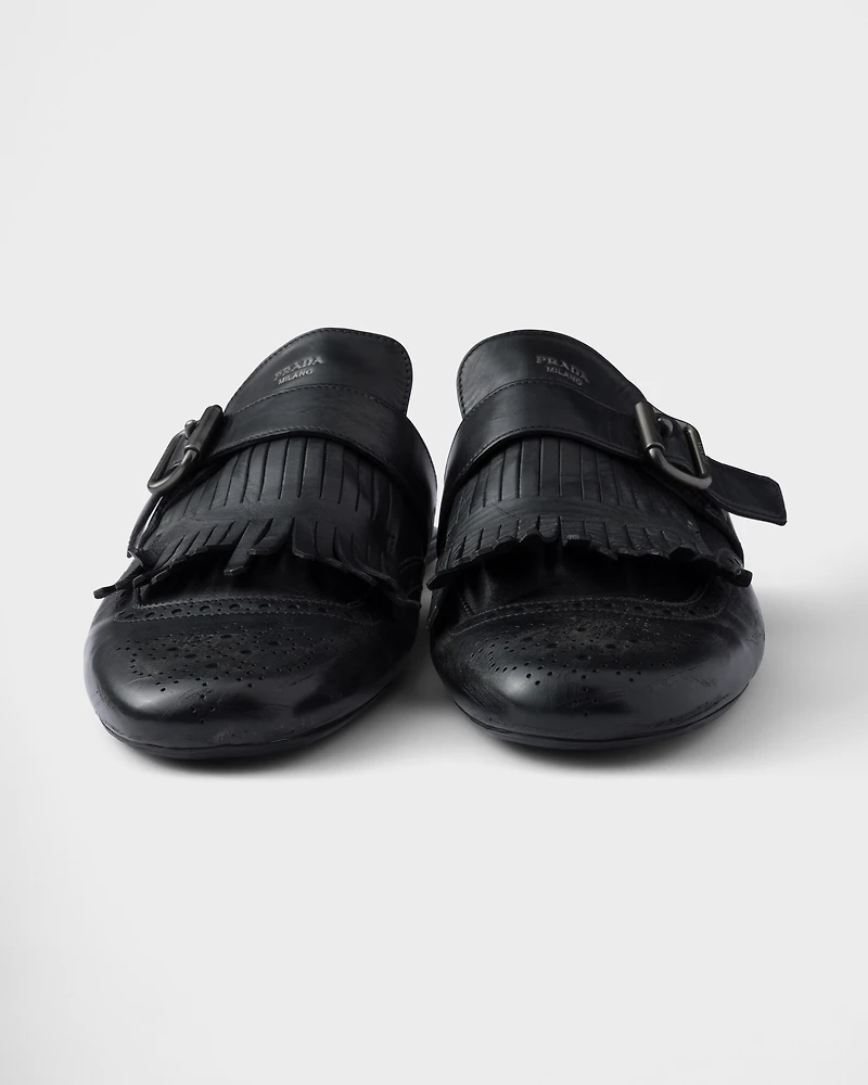 Shuffle antiqued leather mules with buckled strap and fringe