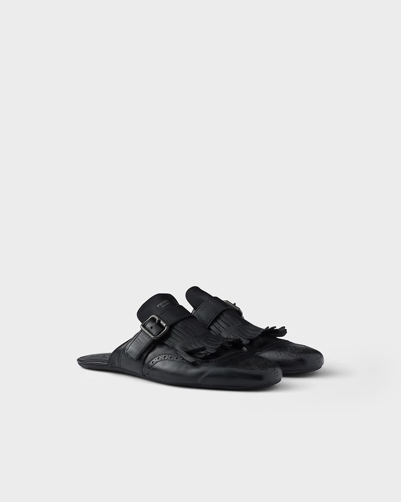 Shuffle antiqued leather mules with buckled strap and fringe