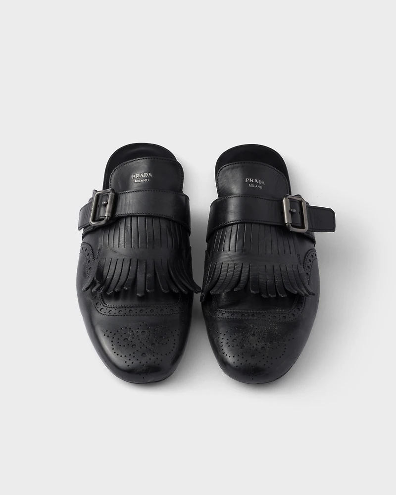 Shuffle antiqued leather mules with buckled strap and fringe