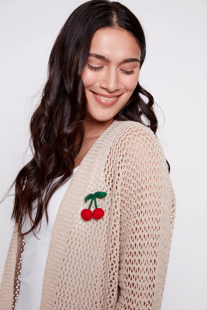 Le cardigan en maille avec broche cerise