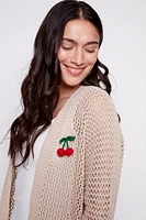 Le cardigan en maille avec broche cerise