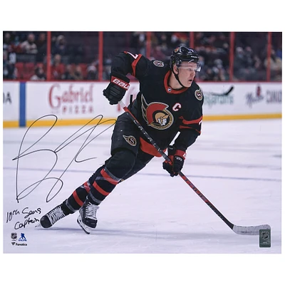 Photographie de patinage autographiée de 16 po x 20 po de Brady Tkachuk, maillot noir des Sénateurs d'Ottawa, avec l'inscription « 10th Sens Captain »