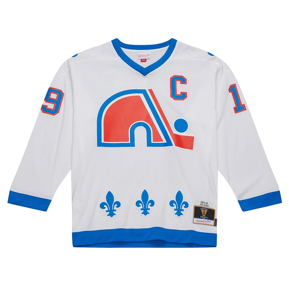 Maillot de joueur la ligne bleue Mitchell & Ness Joe Sakic, blanc, Patch du capitaine des Nordiques Québec 1994/95 pour hommes