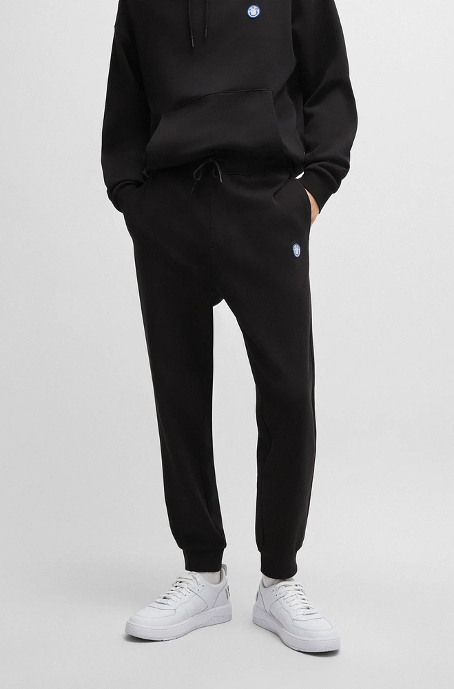 Cotton-terry tracksuit bottoms with smiley-face logo patch