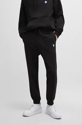 Cotton-terry tracksuit bottoms with smiley-face logo patch