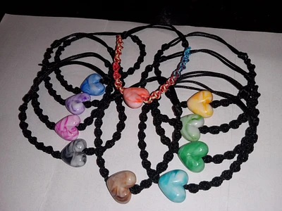 Handmade adjustable cord bracelets with one large acrylic heart shape bead .