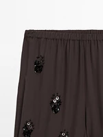 Flowing trousers with floral appliqués
