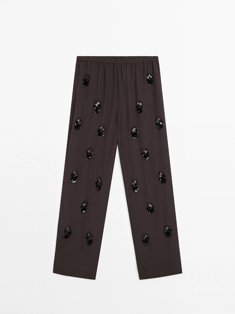 Flowing trousers with floral appliqués