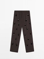 Flowing trousers with floral appliqués
