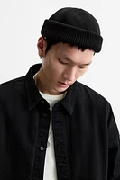 Hat made of tonal matching fabrics with turned-up knit brim. Adjusts with loop.