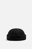 Hat made of tonal matching fabrics with turned-up knit brim. Adjusts with loop.