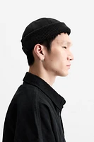 Hat made of tonal matching fabrics with turned-up knit brim. Adjusts with loop.