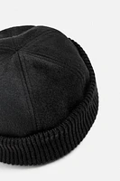 Hat made of tonal matching fabrics with turned-up knit brim. Adjusts with loop.