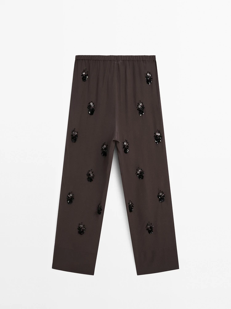 Flowing trousers with floral appliqués