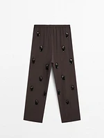 Flowing trousers with floral appliqués