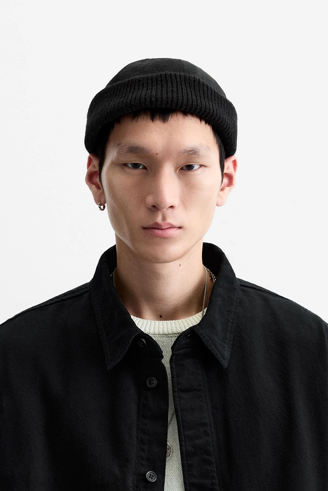 Hat made of tonal matching fabrics with turned-up knit brim. Adjusts with loop.